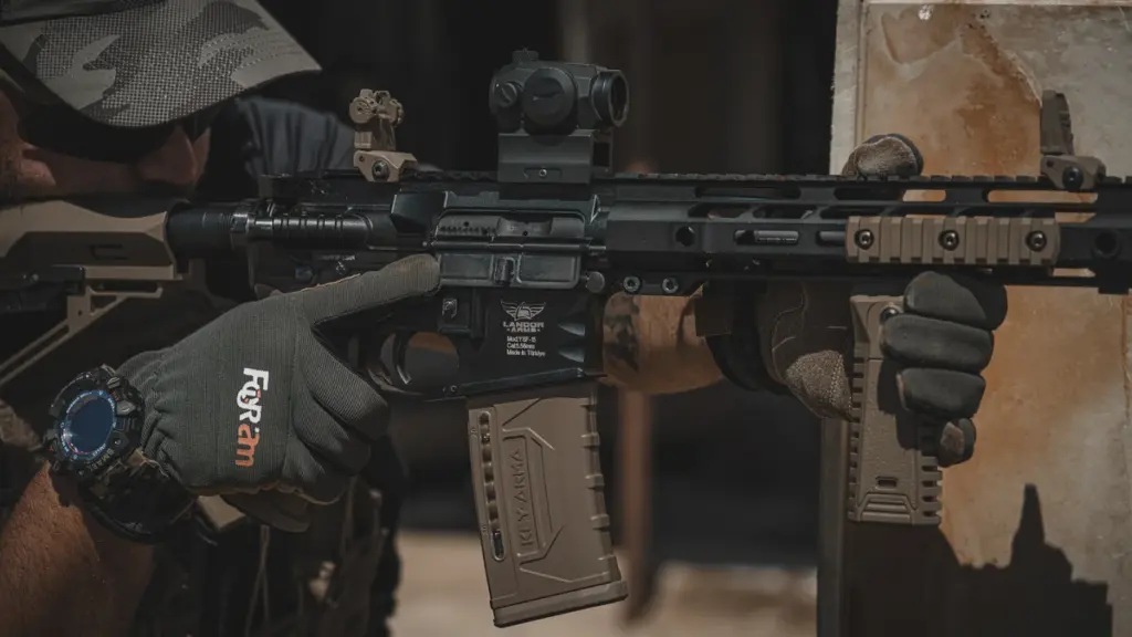 Operator aiming an AR-15 with a polymer magazine and red dot optic